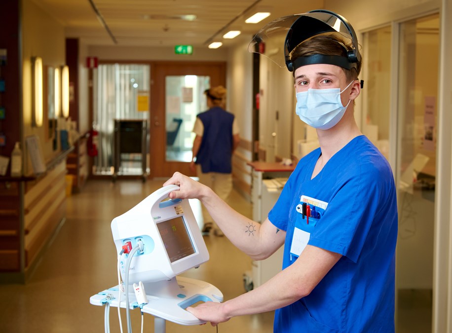 Sjuksköterska med apparat i korridor.