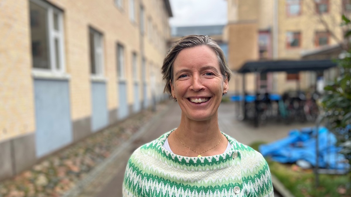 Katarina Nyström står utomhus i ett blåsigt Göteborg i november. Hon ler med hela ansiktet och ser väldigt glad ut.