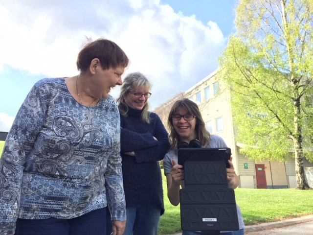 Tre glada personer samlats runt en surfplatta