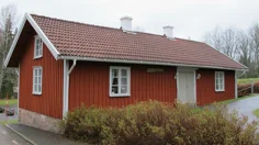 Röd stuga med tegeltak och texten sockenstuga på fasaden