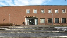 Tegelbyggnad i rött och med texten bibliotek över entrén