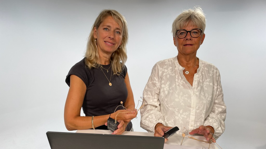 Två personer vid ståbord framför vit vägg.