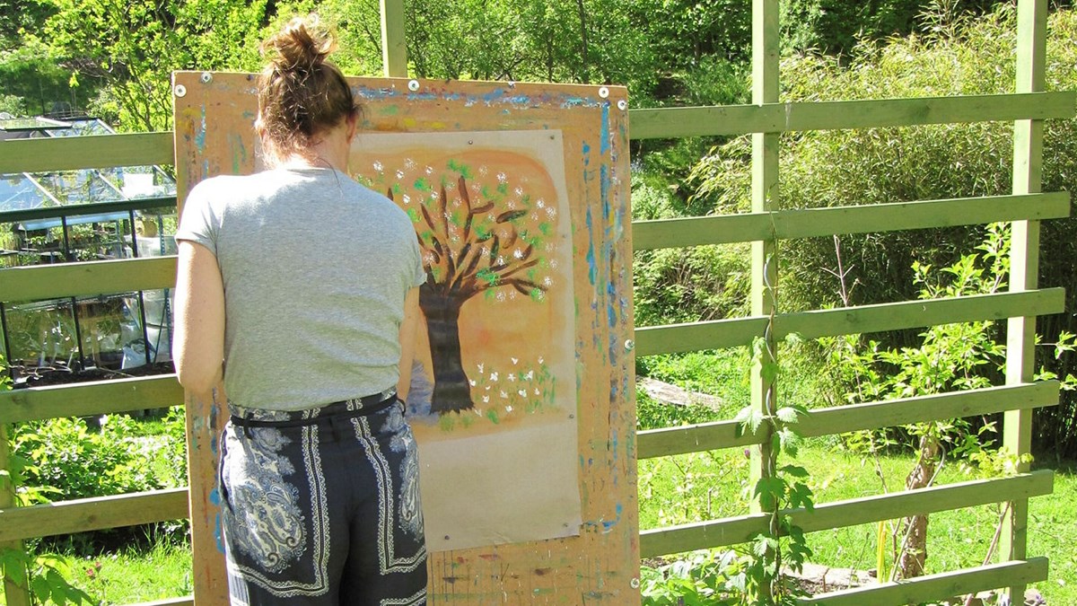 Kvinna målar ett träd utomhus