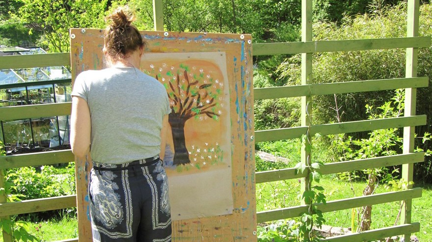 Kvinna målar ett träd utomhus