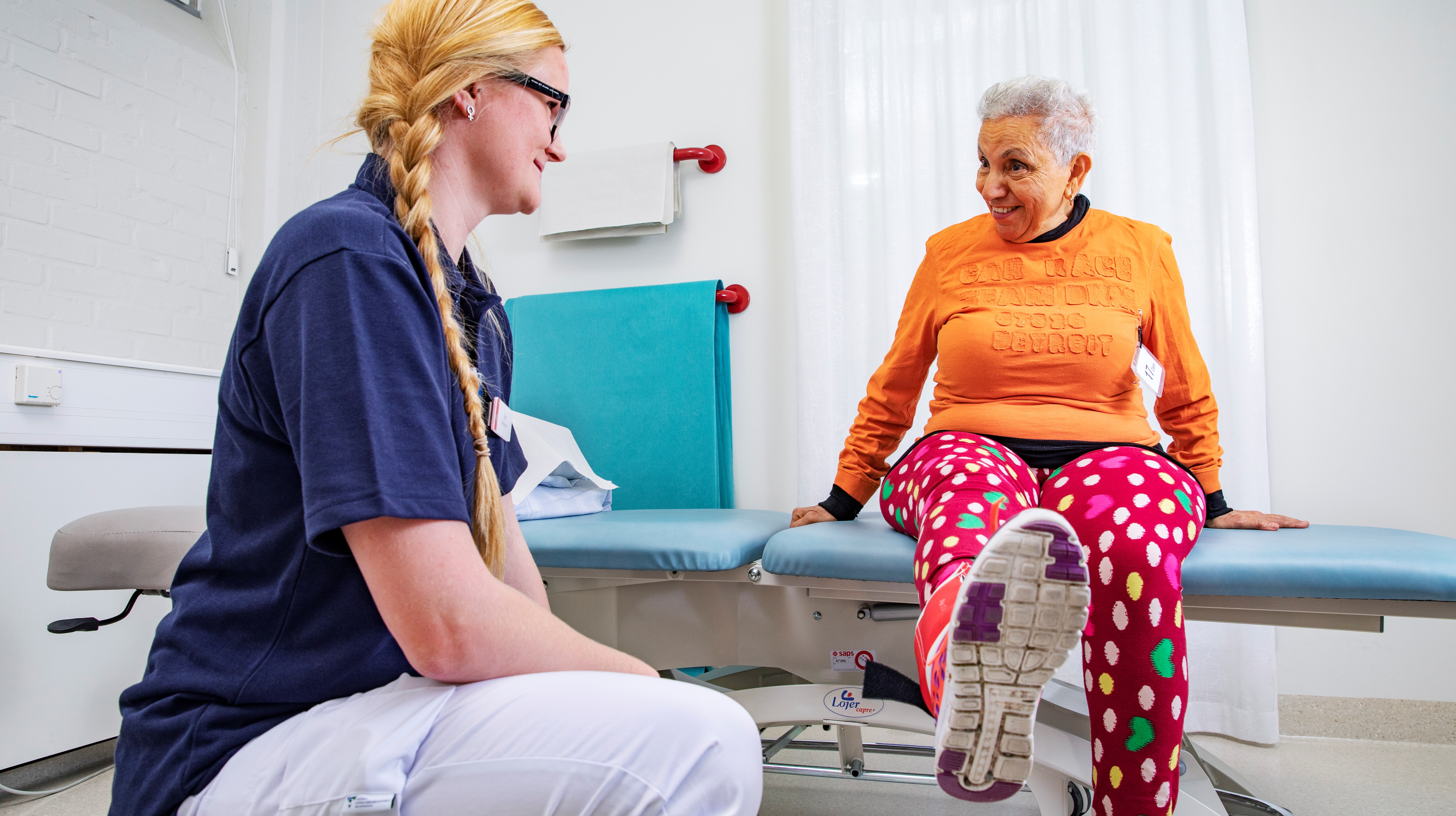 En patient på en brist sträcker på ena benet för att rehabiliteringsträna.