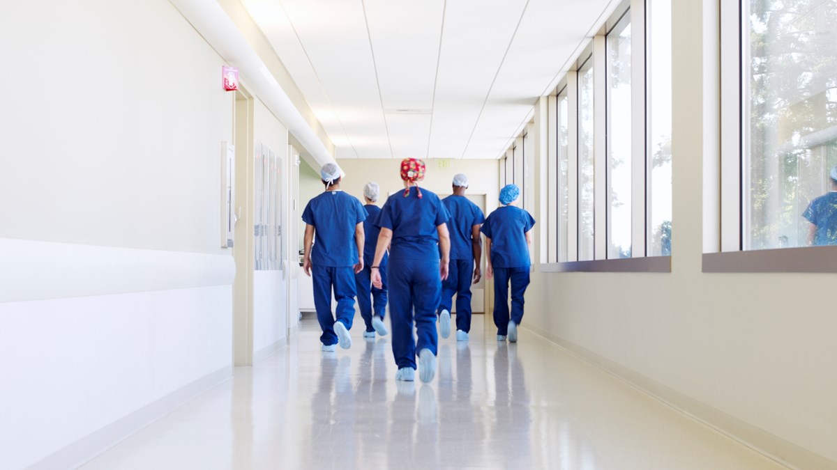 en grupp i blå sjukhuskläder går i en korridor