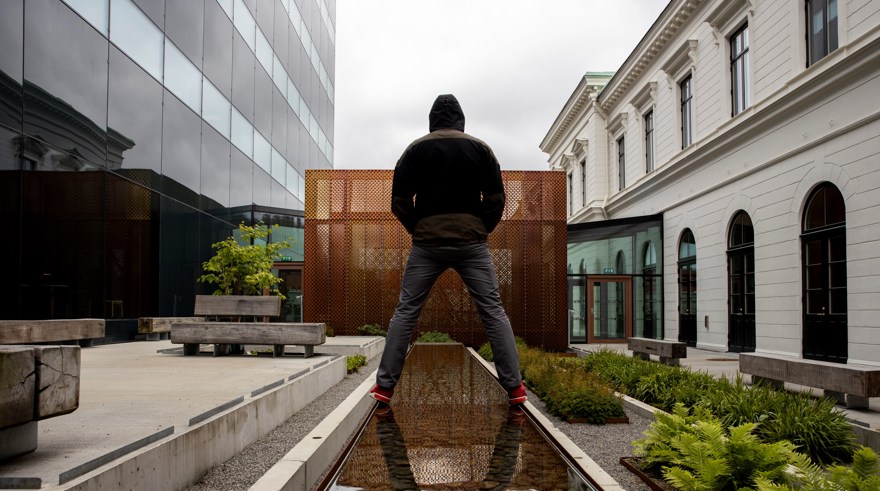 En person står över en vattenspegel på en innegård mellan två kontorshus.