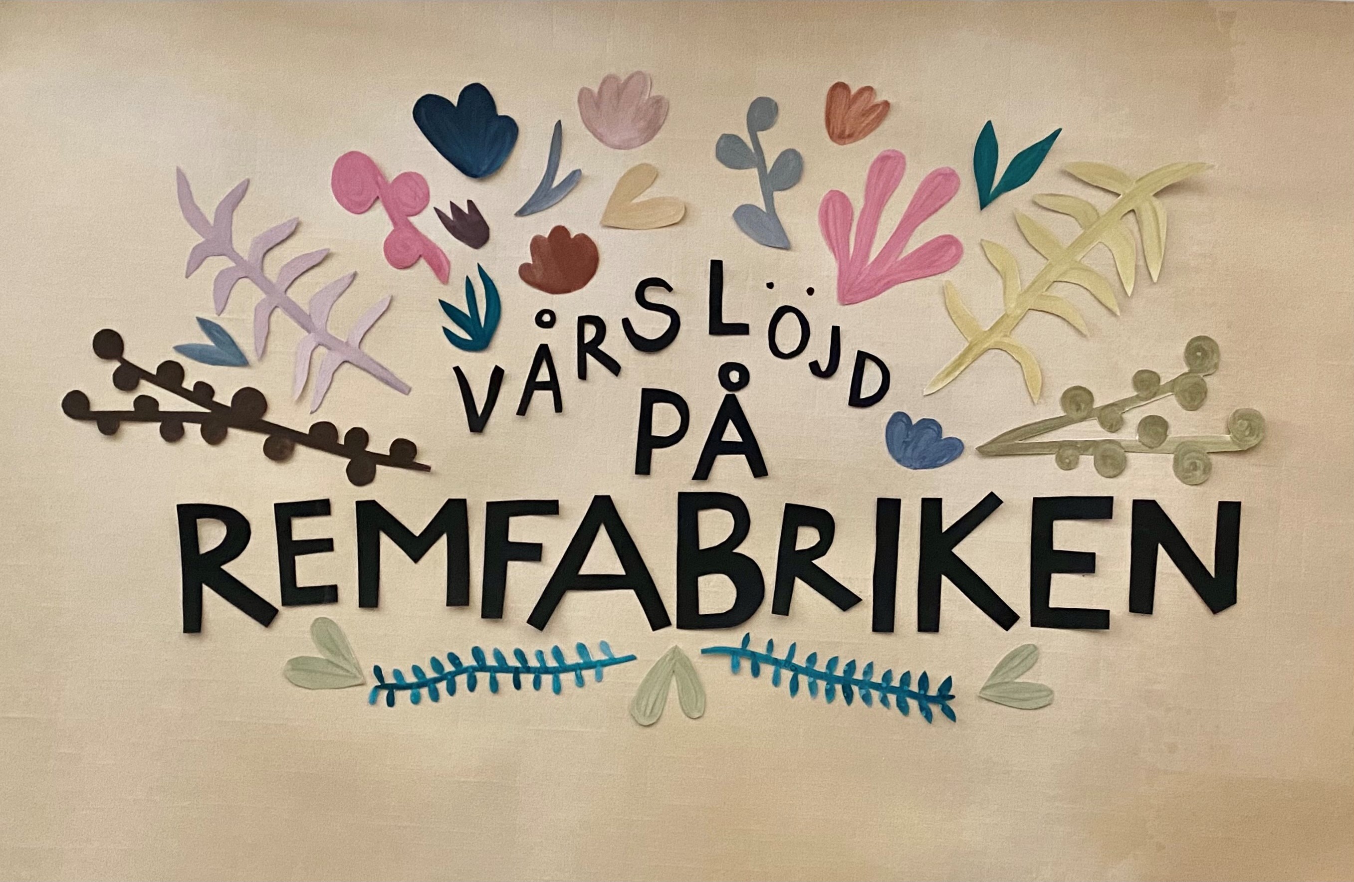 Pappersklipp med texten vårslöjd på remfabriken i svart omgivet av klippta blom- och bladfärger i pastellfärger