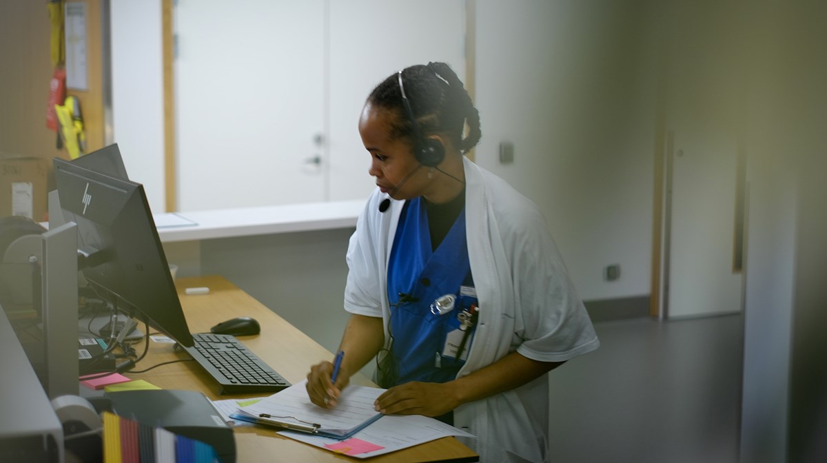 En sjuksköterska i samtal framför dator