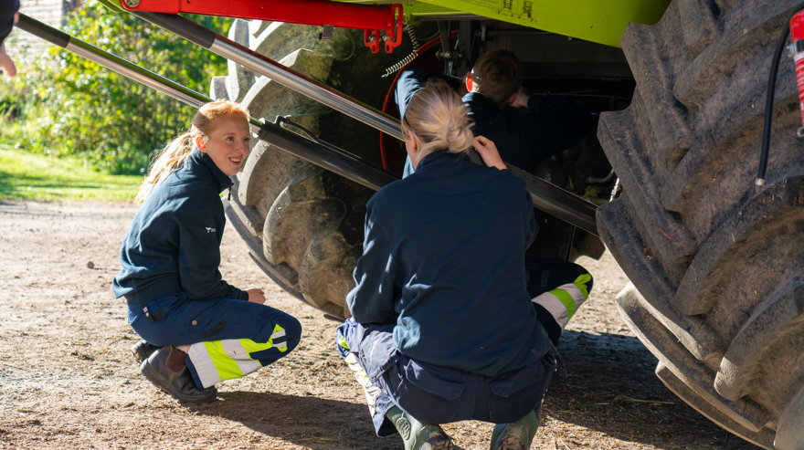Två elever sitter under skördetröska