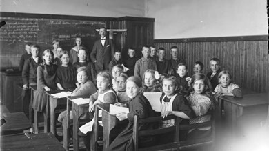 Svartvit bild från gammal skola föreställande lärare och barn