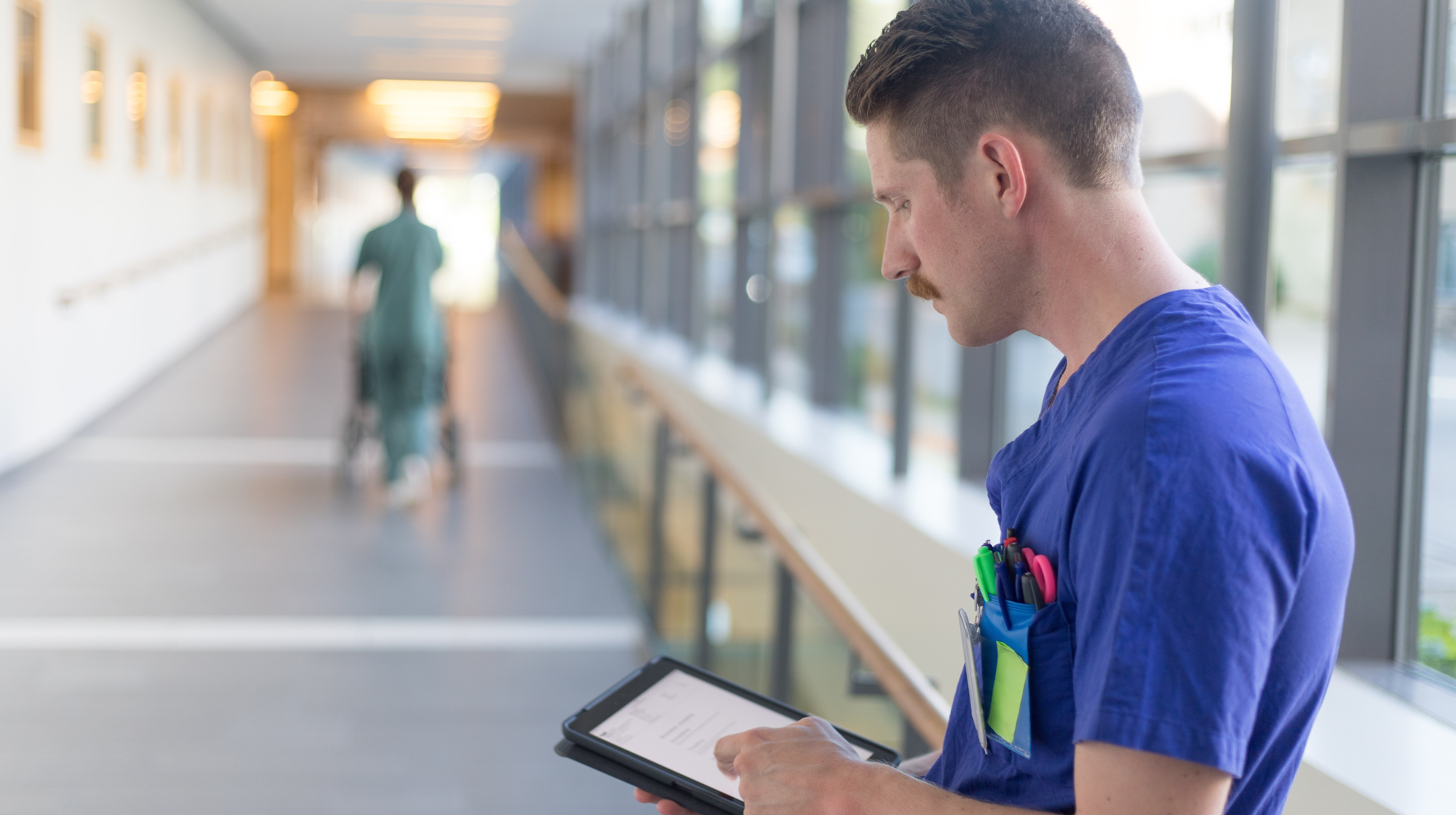 Vårdspersonal tittar på surfplatta i sjukhuskorridor
