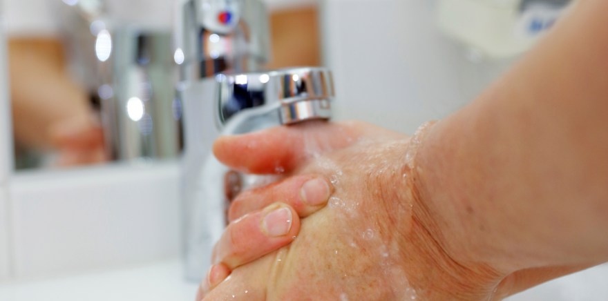 Händer under en rinnande vattenkran.