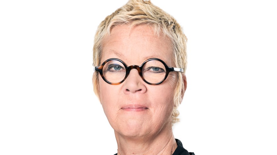 Kvinna, blont kort hår. Svarta, runda glasögon