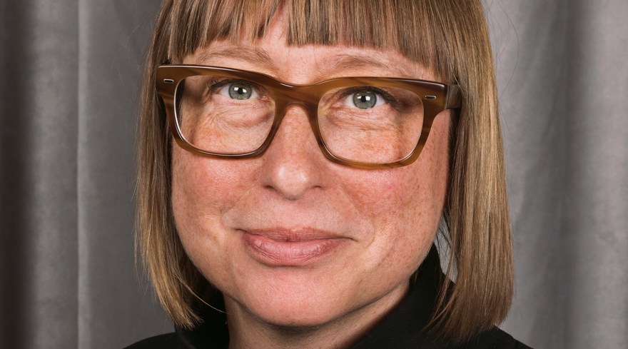 Kvinna, brunt hår, lugg, glasögon och svart tröja