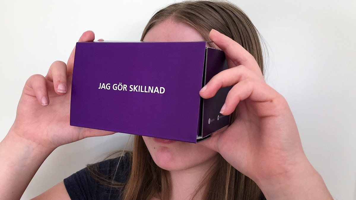 Flicka med VR-glasögon av kartong.