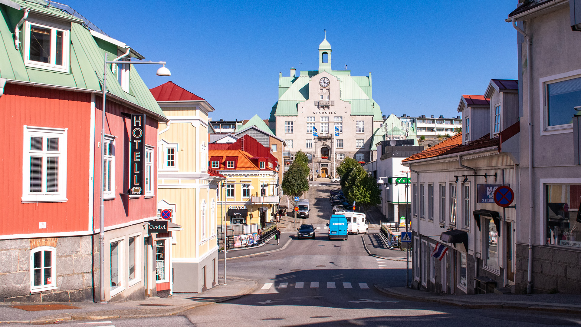 Strömstad centrum. Trähus i olika kulörer, rött, gult och beige. Längst bort i bild tornar en stor beige byggnad upp med torn och klocka på utsidan.