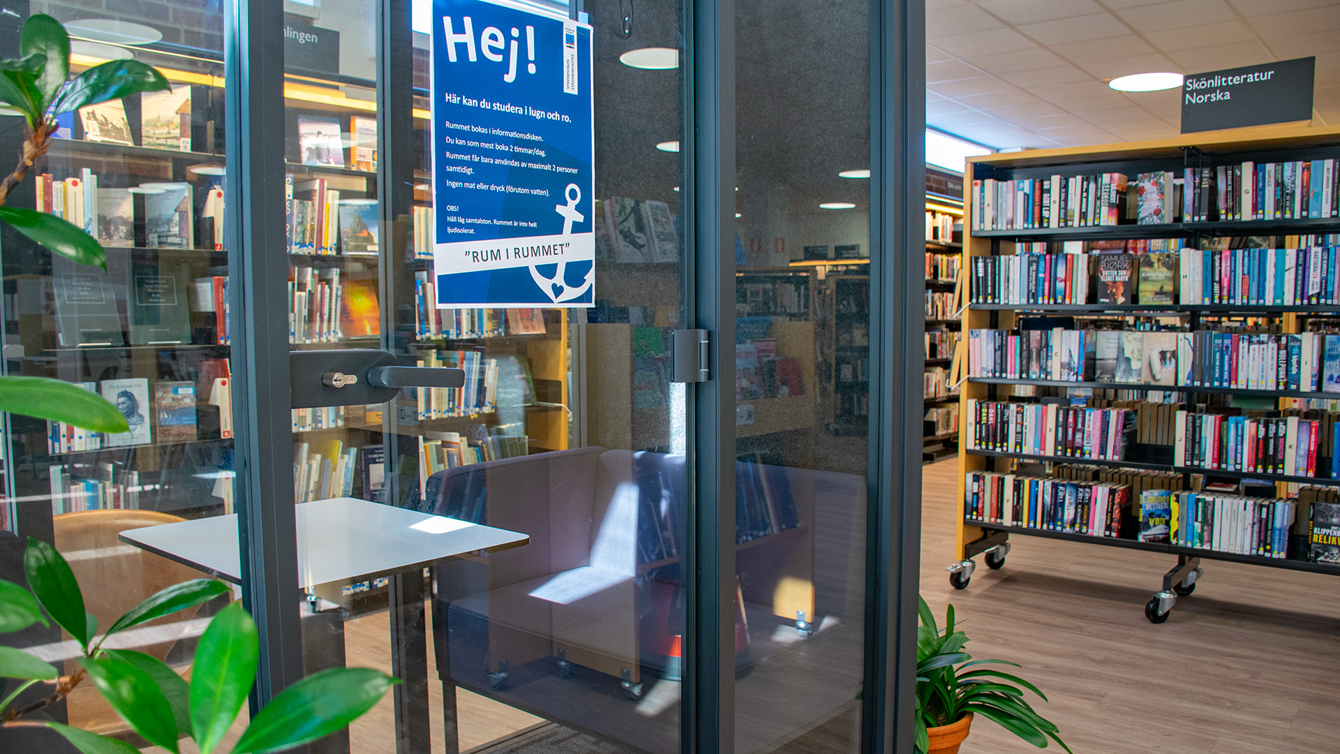 I biblioteksrummet finns ett glasrum för max två personer där man kan plugga eller läsa ifred. Två sittfåtöljer står mitt emot varandra i glasrummet med ett vitt litet bord emellan.