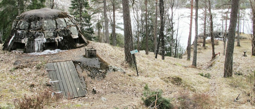 Parsetjärns skans vid sjökanten. En trädörr i en kulle med ett metalltak.