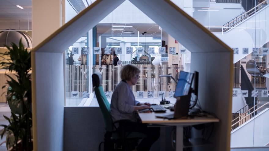 Kvinna arbetar vid skrivbord med ett "hus" runt