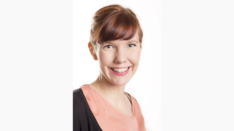 Julia Pennlert har rödbrunt hår som är uppsatt i en knut. Hon ler mot kameran.