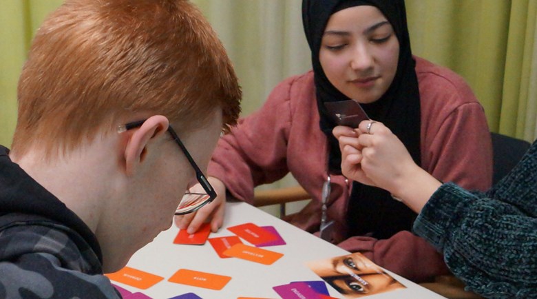 Två elever, en pojke och en flicka tittar på färgglada kort med ord på egenskaper. 