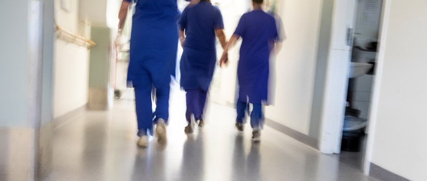 Sjukhuspersonal går i en korridor. Bilden är suddig.