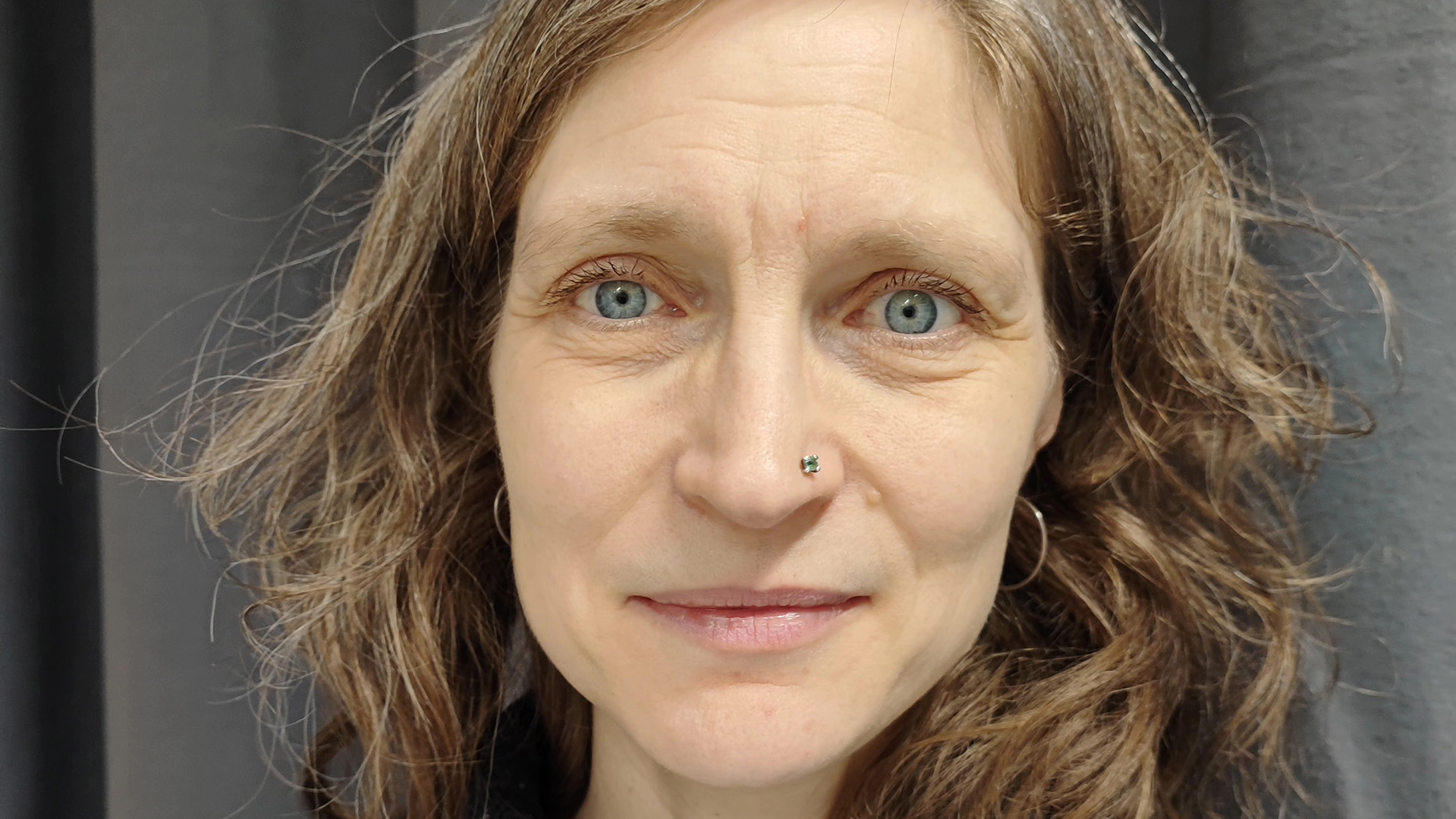 Ellen Spens har ljusbrunt hår till axlarna och blå ögon. Hon tittar rakt mot fotografen och ler med stängd mun. Hon är gissningsvis i yngre medelåldern. I Ellens näsvinge sitter en glittrande sten. 