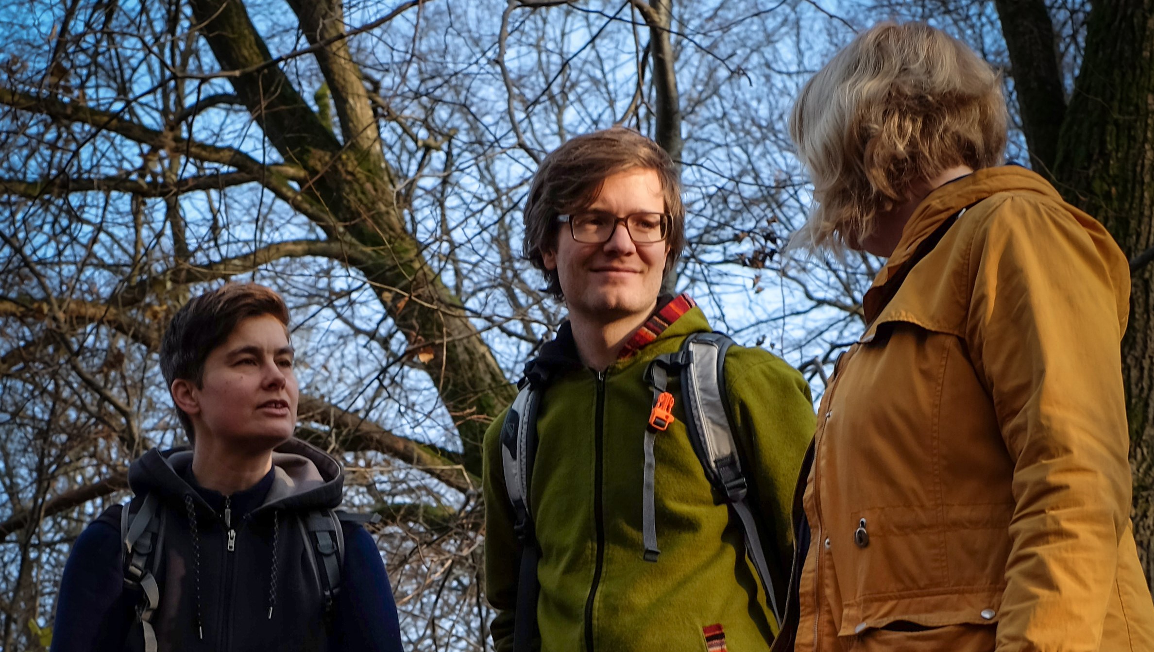 Fotografi taget framifrån på tre personer som samtalar under en promenad