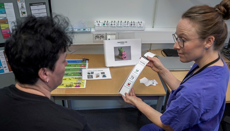 En logoped visar bildstöd för en kvinna