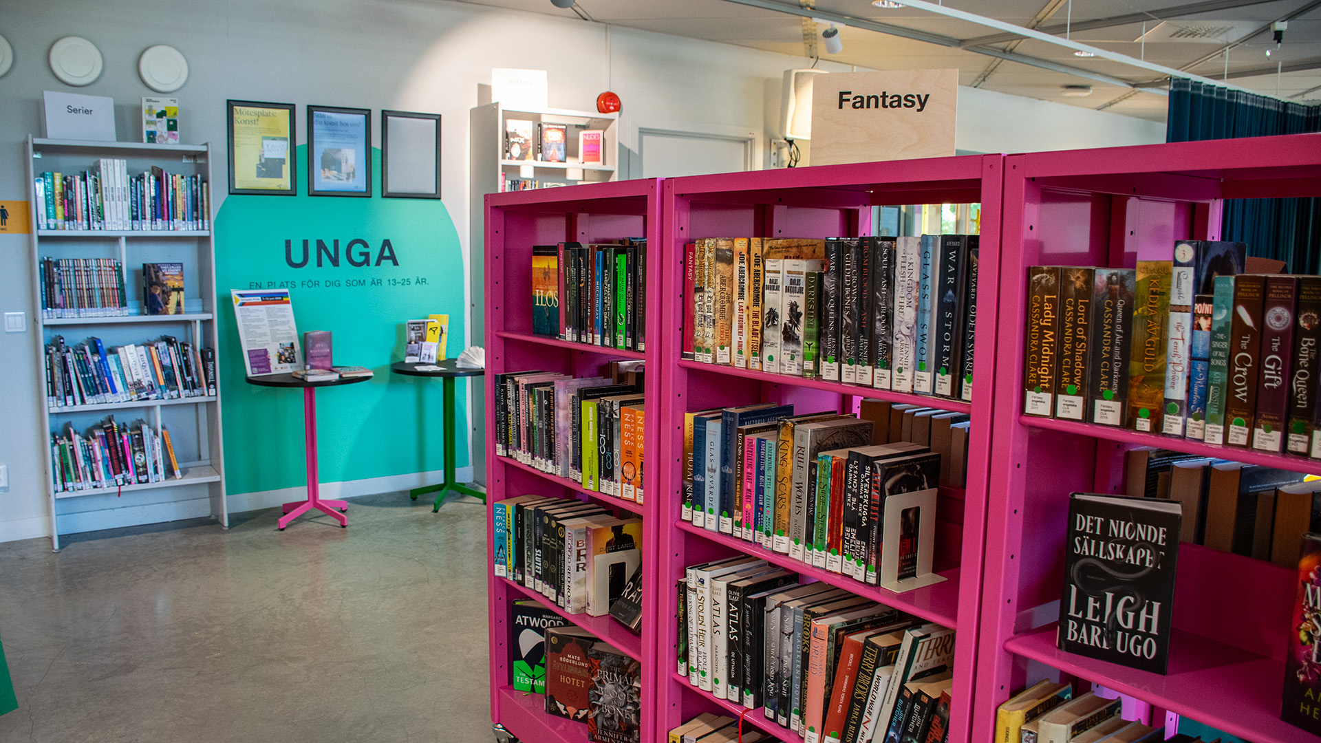 En knallrosa bokhylla fylld med ungdomslitteratur. På en skylt ovanför hyllan står det Fantasy. 