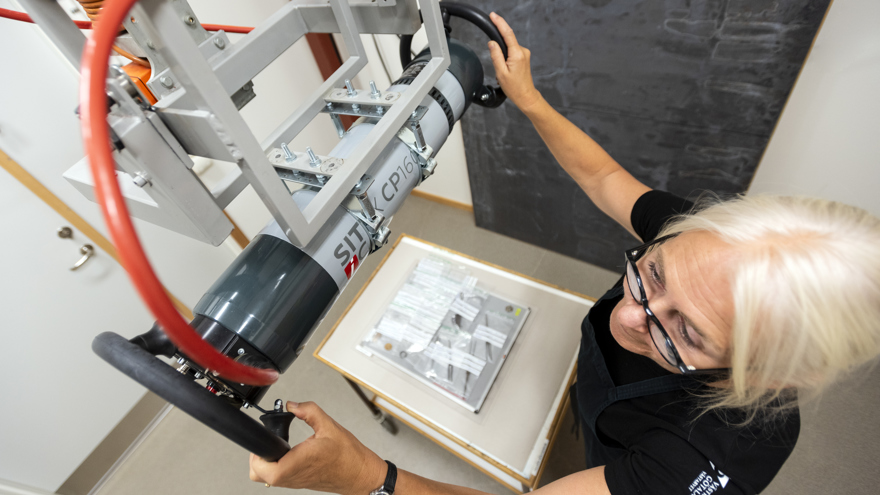 En konservator förbereder röntgenfotografering av en mängd små arkeologiska metallfynd som ligger i plastpåsar.