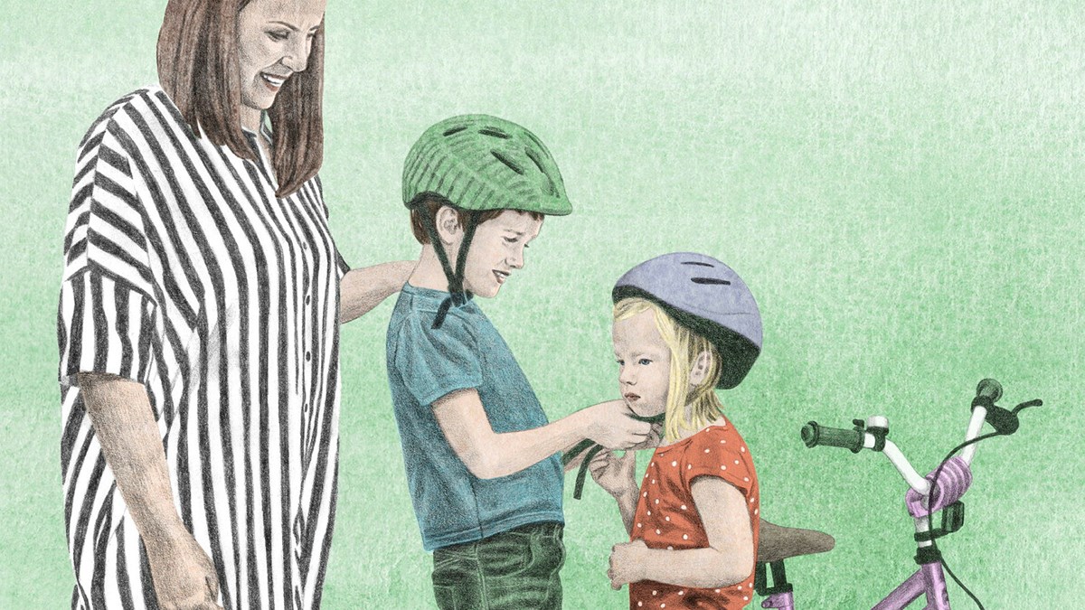 Två barn sätter på sig cykelhjälmar och deras förälder står bredvid.