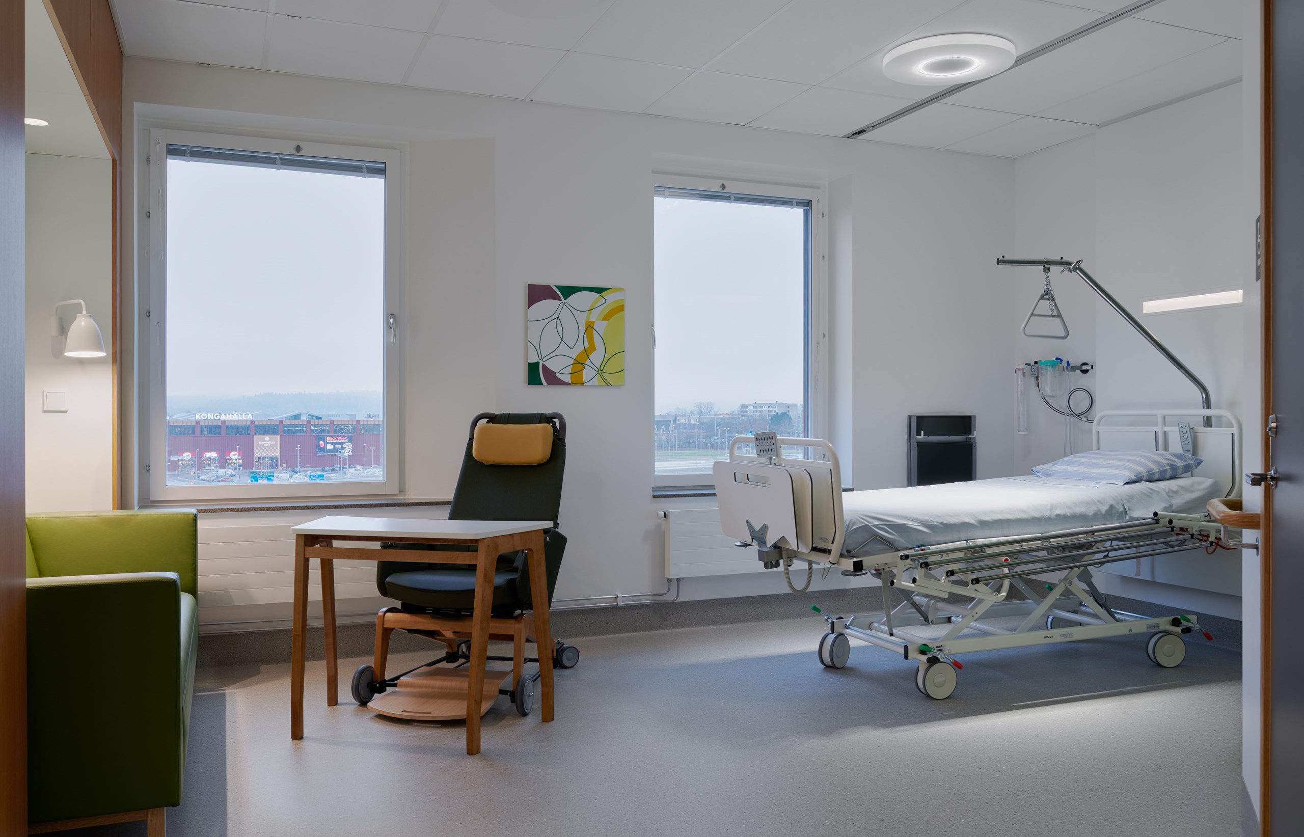 Patientrum med säng, fåtölj, bord och soffa.