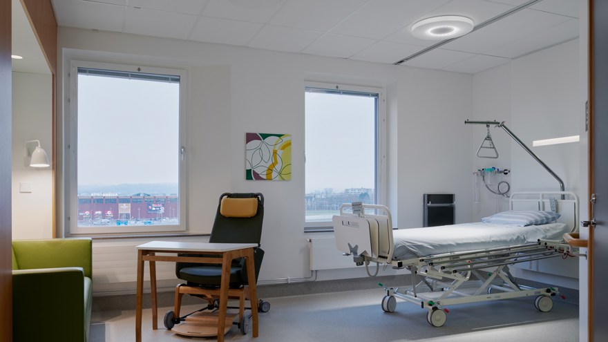 Patientrum med säng, fåtölj, bord och soffa.