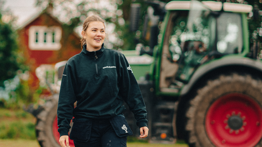 Elev framför traktor och rött hus