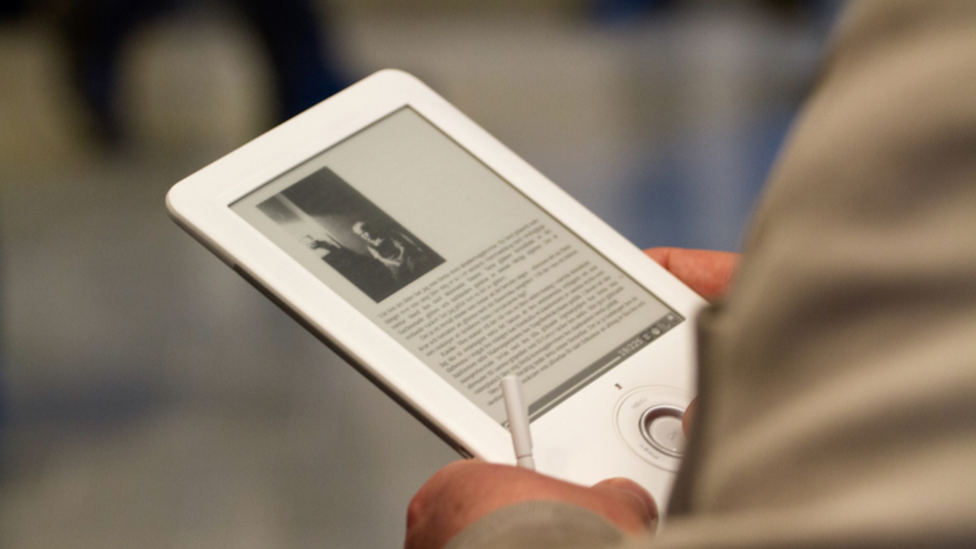 En närbild på en läsplatta. På plattan finns en svartbit bild och text. Någon håller i plattan.