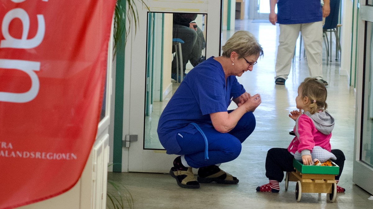 Personal på vårdcentral sitter ner och pratar med ett barn