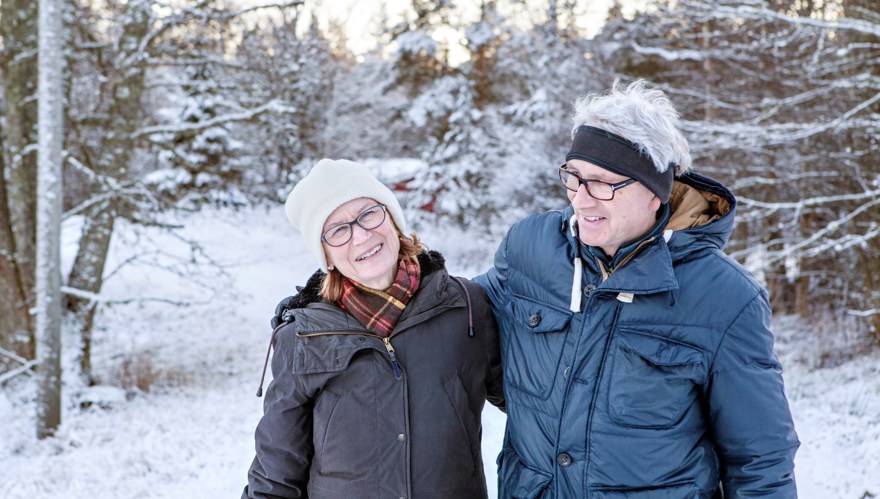 Pensionärspar med snötäckta träd i bakgrunden
