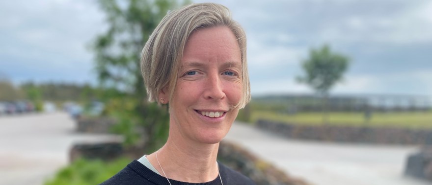 Katarina Nyström står utomhus, håret blåser och himlen är blå.