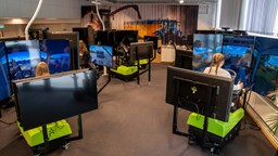Flera simulatorer uppställda i ett rum med elever som sitter framför skärmar i simulatorer