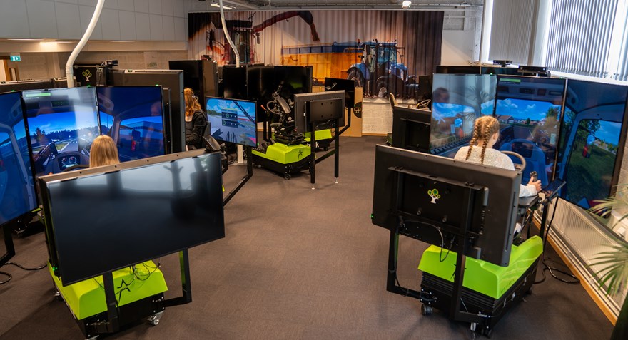 Flera simulatorer uppställda i ett rum med elever som sitter framför skärmar i simulatorer