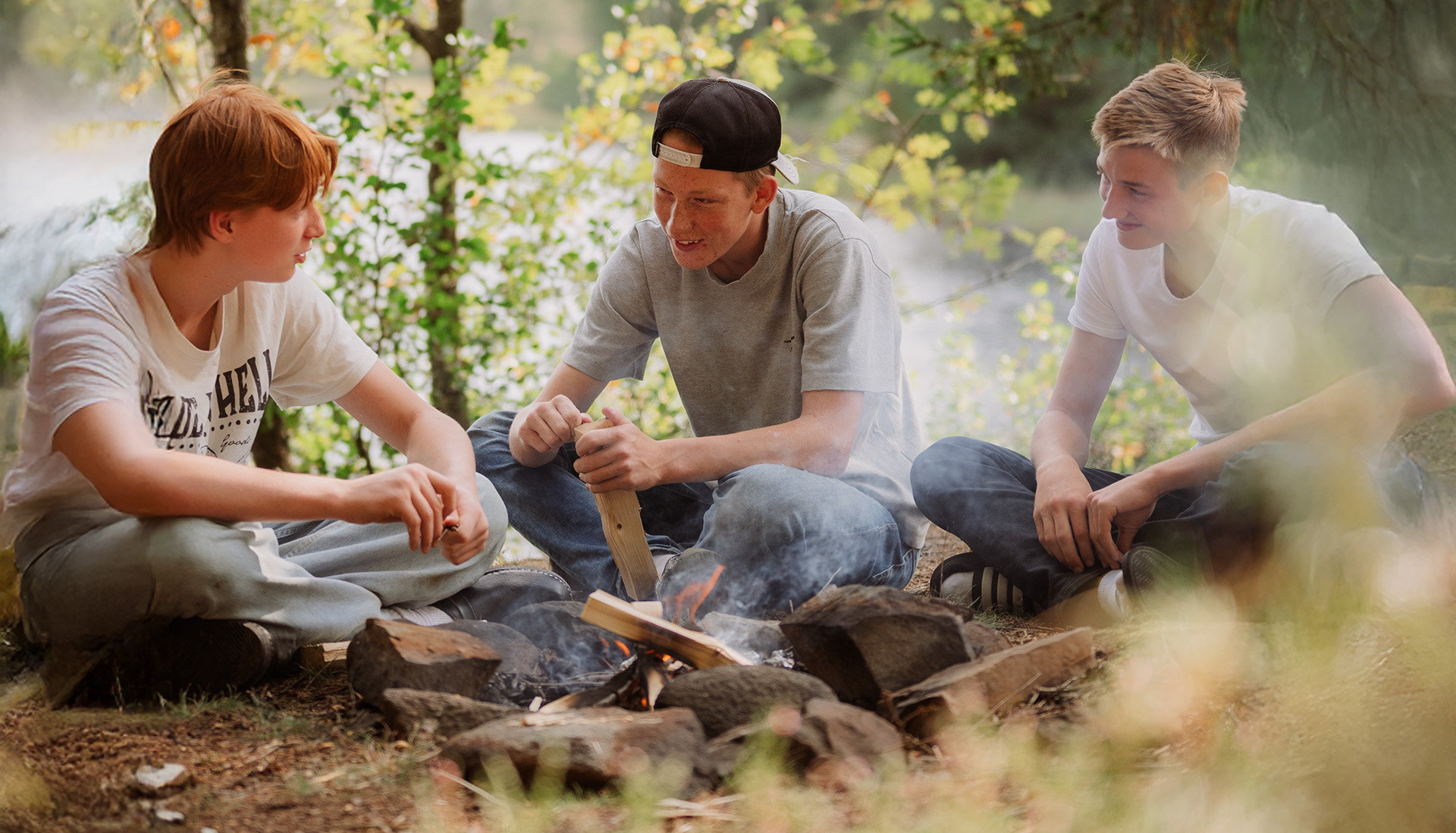three students are sitting together at a campfire