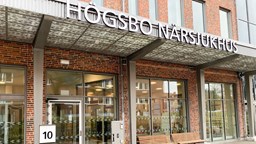 Entre till Högsbo närsjukhus. Tegelvägg, glasdörrar och sjukhusets namn i tora metallgrå bokstäver.