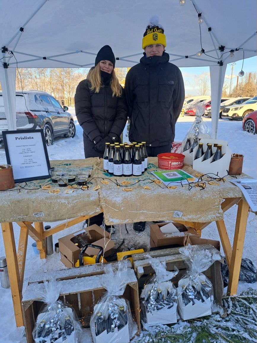 Två elever visar upp sina produkter på ett bord