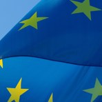 Den blåa Europeiska flaggan vajar i vinden, solen lyser på dom gula stjärnorna.