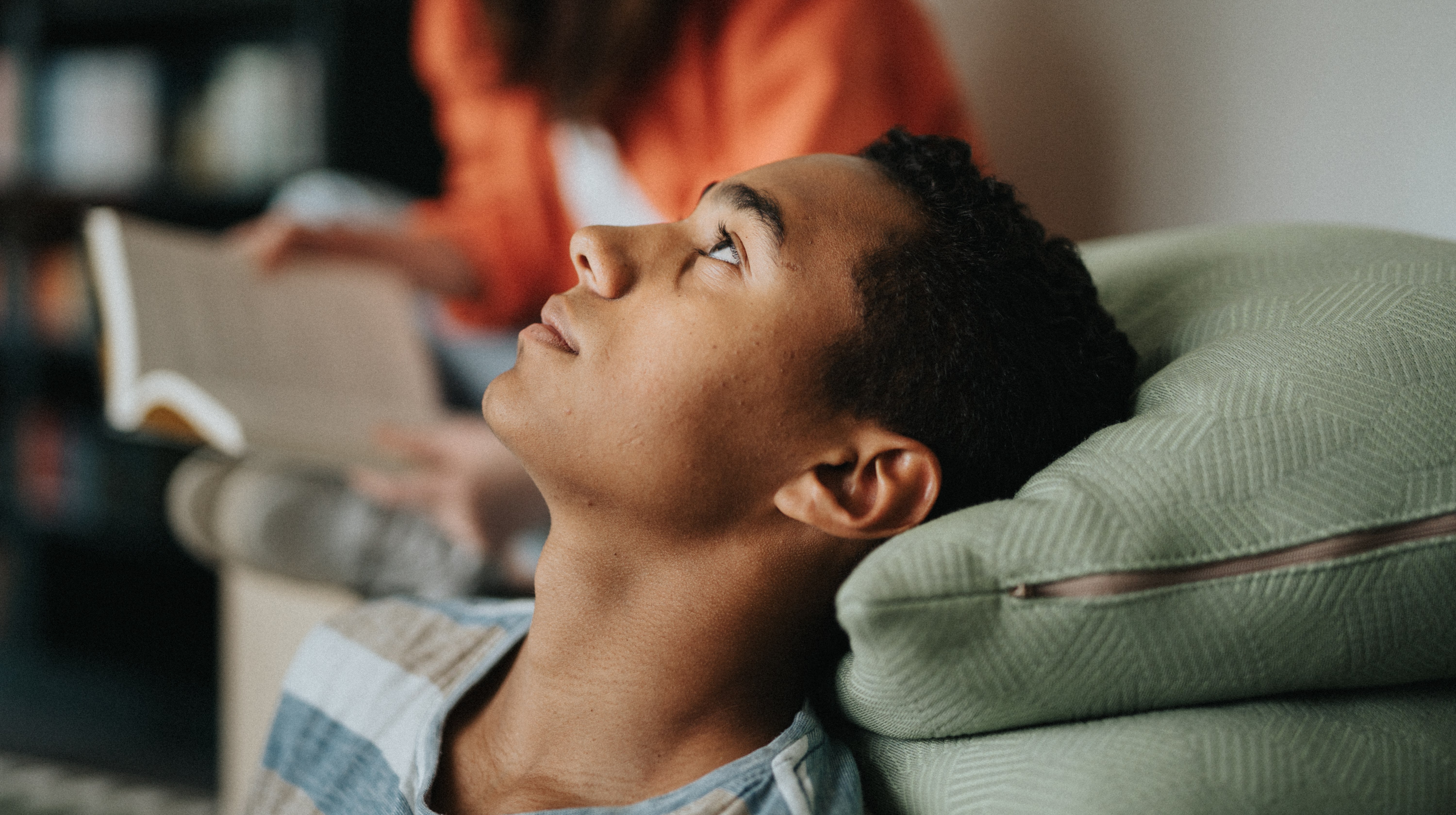 Ung kille funderar med huvudet bakåtlutat i en soffa