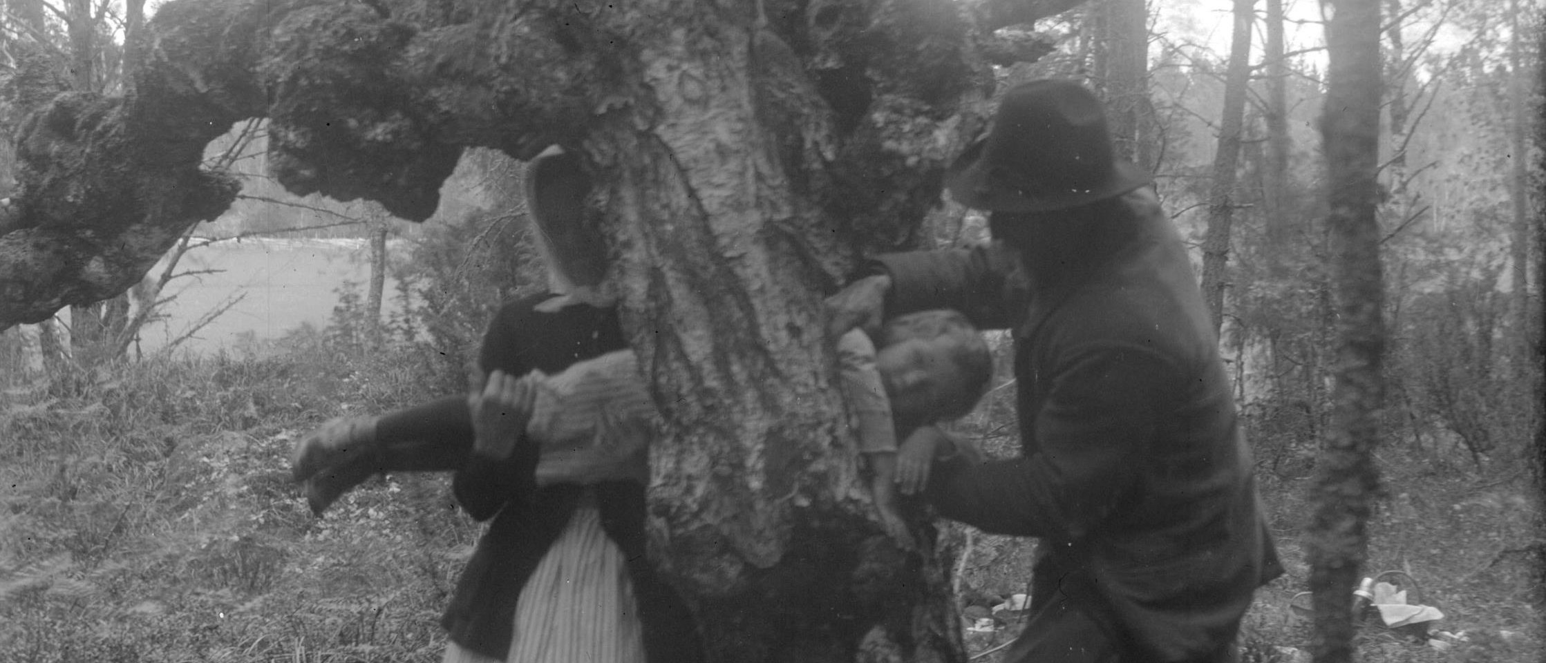 En kvinna och en man för ett barn genom ett hål i ett träd.