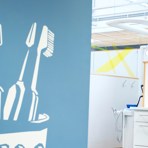 En ljusblå bakgrund med ett ritat tandborstglas i vitt, i glaset står 4 stycken vita ritade tandborstar, dom ser helt nya och oanvända ut.