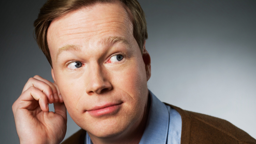 Johan Glans är i 50-årsåldern. Han har blont kortklippt hår som är bakåtkammat. Han är klädd i en blå skjorta och en brun tröja. Ögonen är blå och hans blick tittar snett åt sidan. Bakgrunden i bilden är grå och känns som en fotostudio.